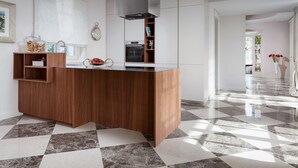 Una cocina moderna con una isla de madera, horno empotrado y un ventanal grande.