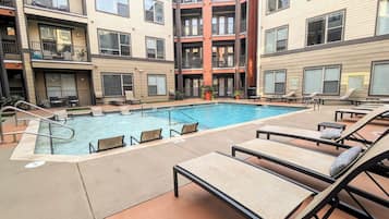 A pool area with lounge chairs and a pool.