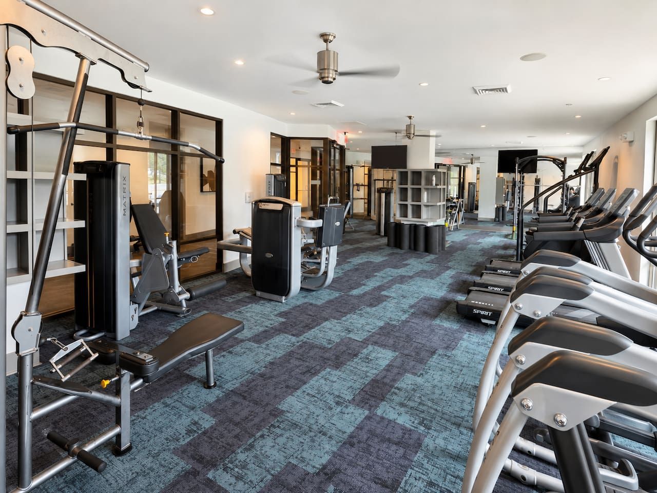 Un gimnasio con cintas de correr, máquinas de pesas y un banco.