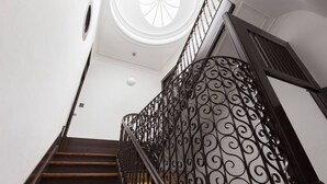A staircase with ornate black metal railings, a wooden handrail, and a white wall. - GuestReady - Innvict Astern (Porto)