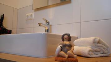 Ein Badezimmer mit einem weißen Waschbecken, einem Spiegel darüber und einer kleinen Figur auf einer Seifenschale.