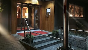 Entrada de un hotel con alfombra roja, paneles de madera y una escalera que conduce a la recepción.