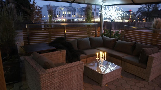 Un área de estar al aire libre con mobiliario de mimbre, una mesa y un candelabro.
