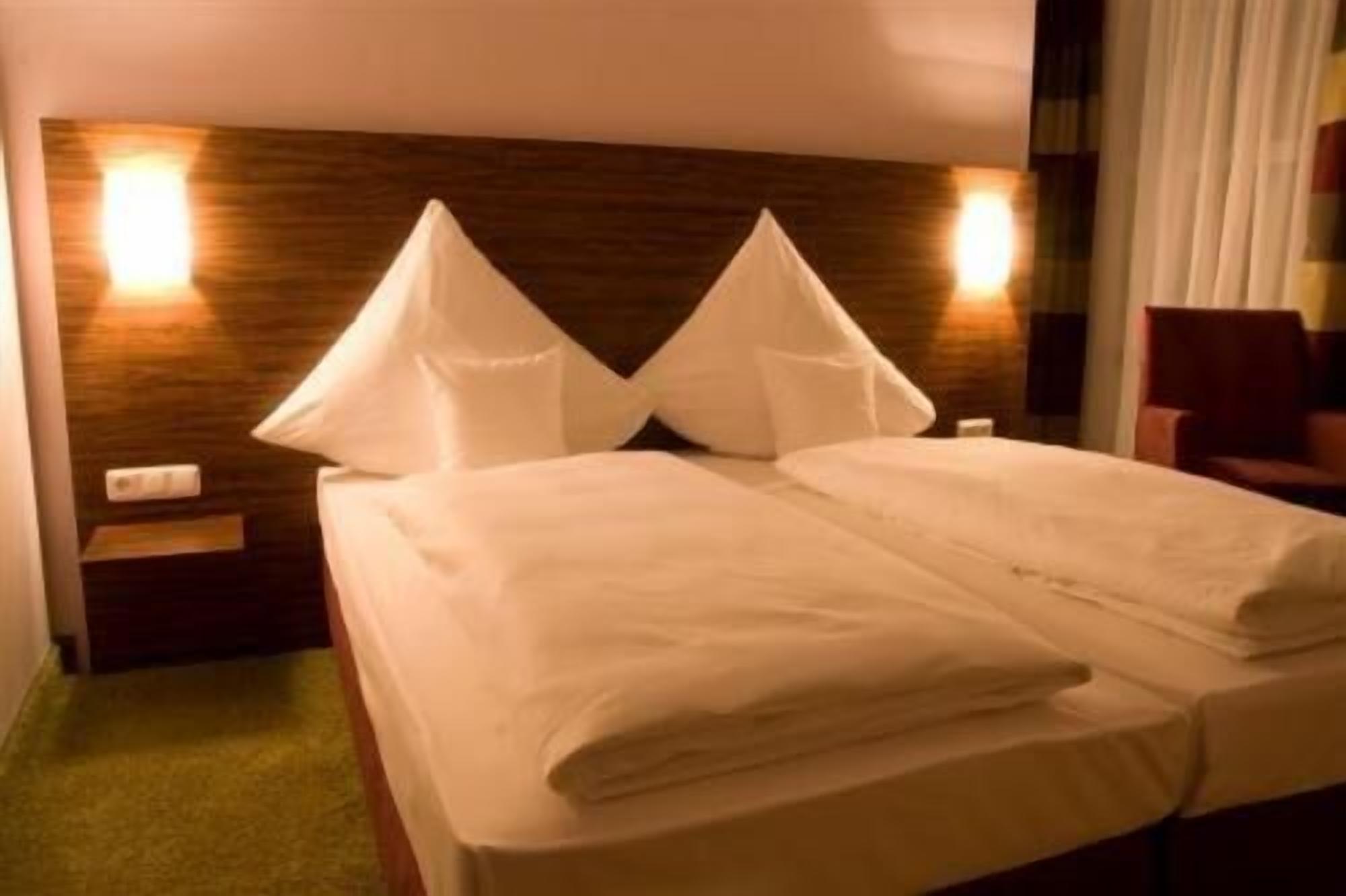 Una habitación de hotel con una cama, dos mesitas de noche y una mesilla.