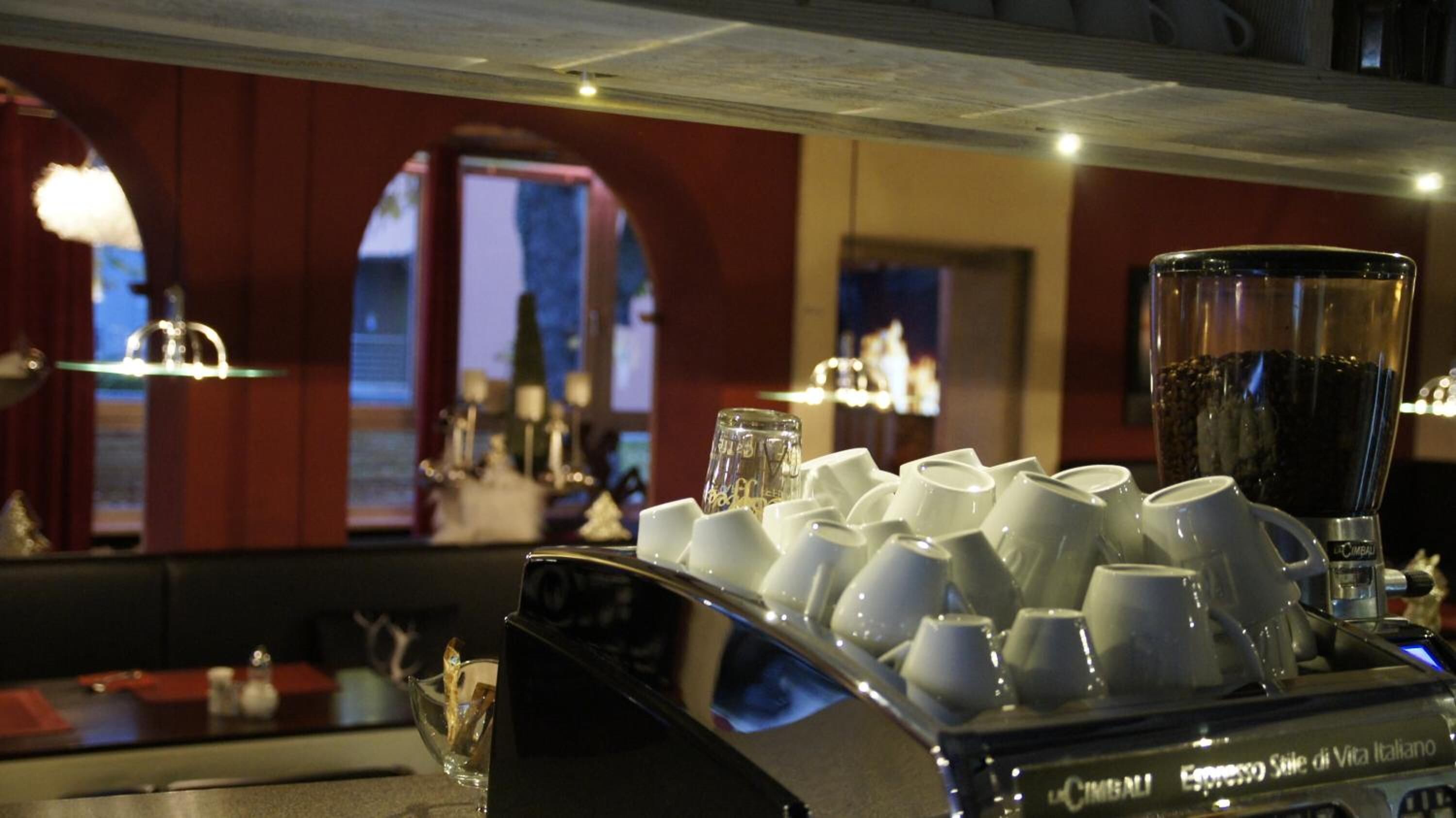 A bar area with a coffee machine and stacked cups.