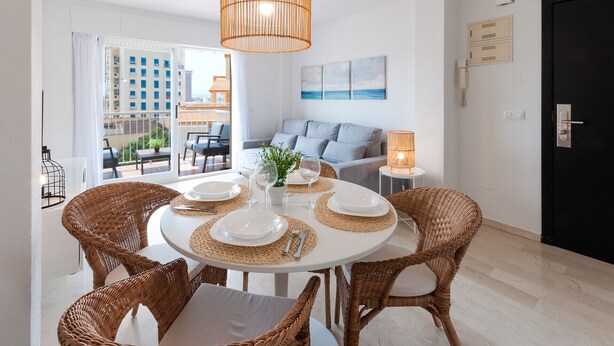 Un coin repas avec une table ronde, des chaises en osier et un luminaire suspendu.