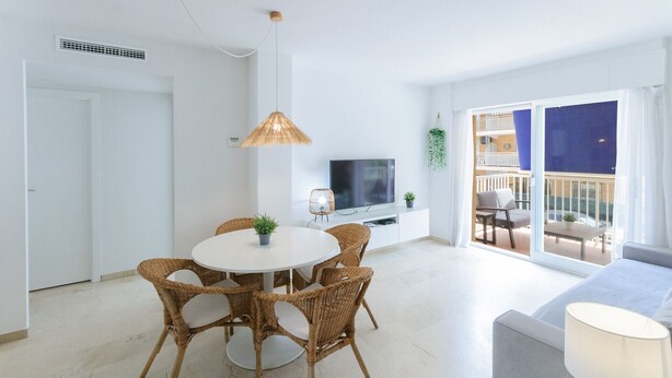 A modern living room with a round dining table, wicker chairs, a flat-screen TV, and a balcony with outdoor seating. - Fabulous and with charm, a few meters from the beach. A / C and free wifi. Terrace with sea views - only families (Playa de Gandía)