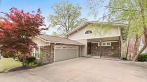 Une maison à deux étages avec une façade en pierre, un garage et une allée.