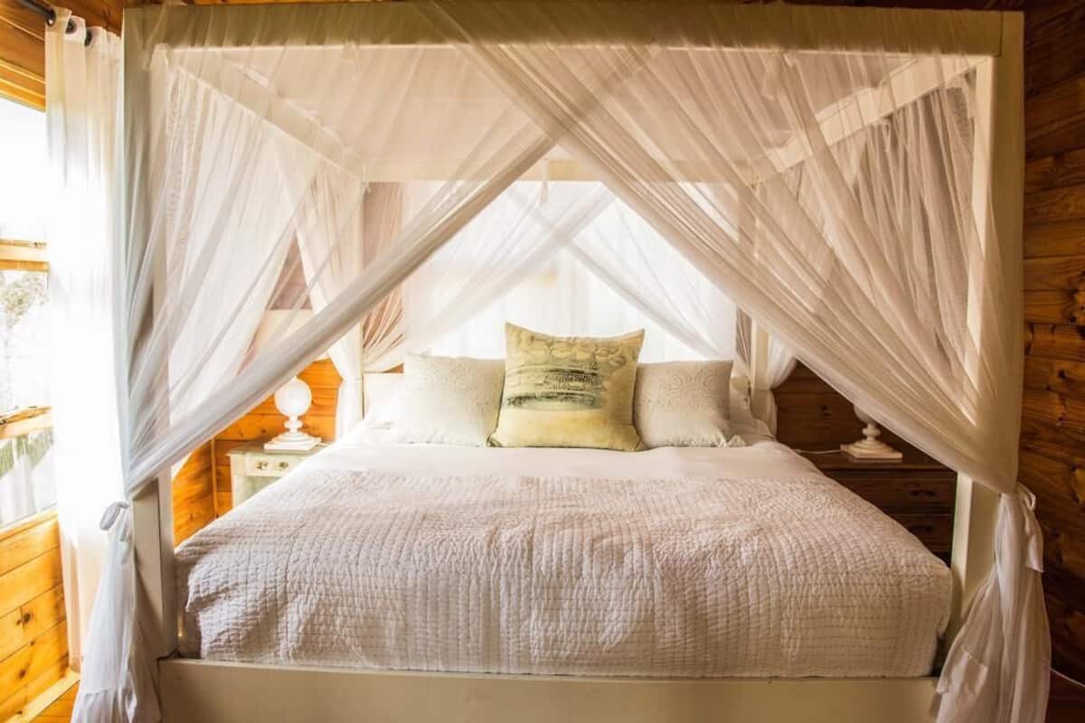 A four-poster canopy bed with white bedding and a wooden headboard.
