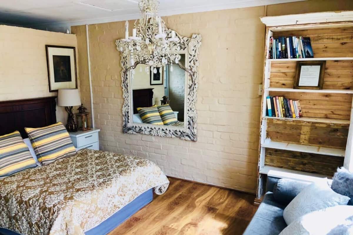 A bedroom with a bed, a bookshelf, a mirror, and a chandelier.