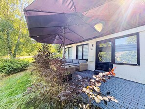 A modern house with a patio, a large umbrella, and a number '50' sign.