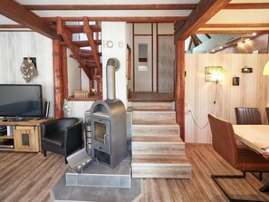 Uma sala de estar aconchegante com lareira, televisão e um espaço de jantar com mesa e cadeiras.