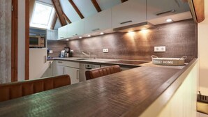 A modern kitchen with wooden beams, a large island, and a view of the outdoors.