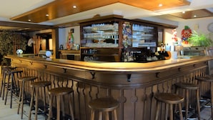 Eine Bar mit einer gebogenen Holztheke, mehreren Barhocker und Regalen voller Gläser und Flaschen.