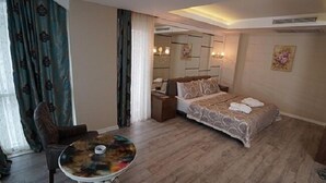 A hotel room with a bed, a round table, a chair, and a mirror. - Otel 1919 (Atakum)