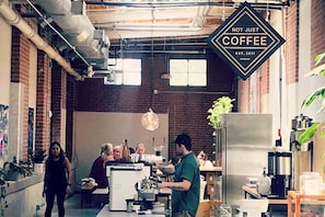 A coffee shop interior with brick walls, industrial-style lighting, and a sign that reads 'NOT JUST COFFEE EST. 2011.'