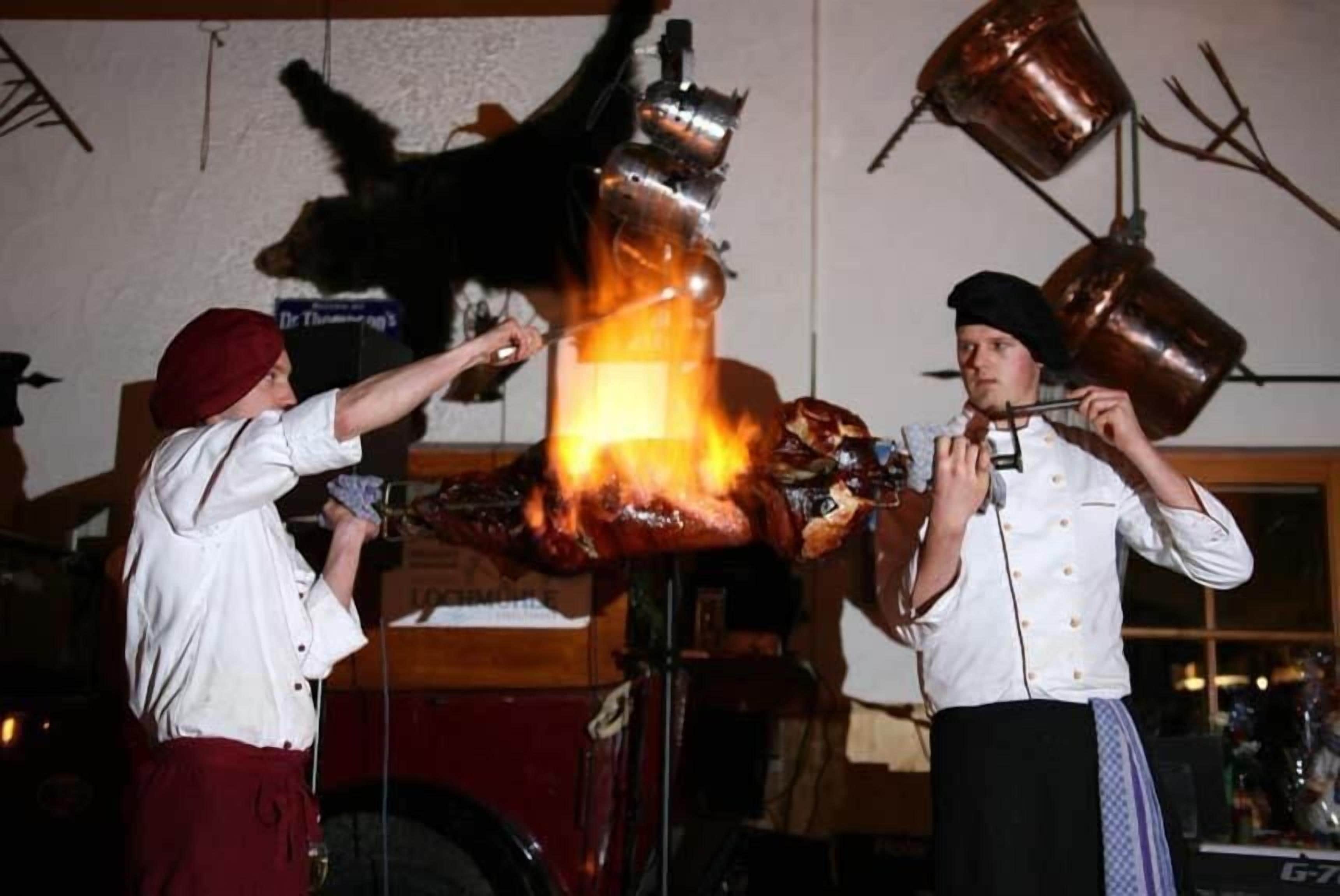 Dos chefs realizando una demostración culinaria con un gran aparato llameante.