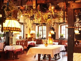 Un restaurante con mesas y sillas de madera, decoraciones colgantes e iluminación cálida.
