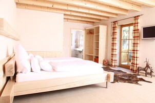 Un dormitorio con una cama de madera, un ventanal con cortinas, un televisor y un armario.