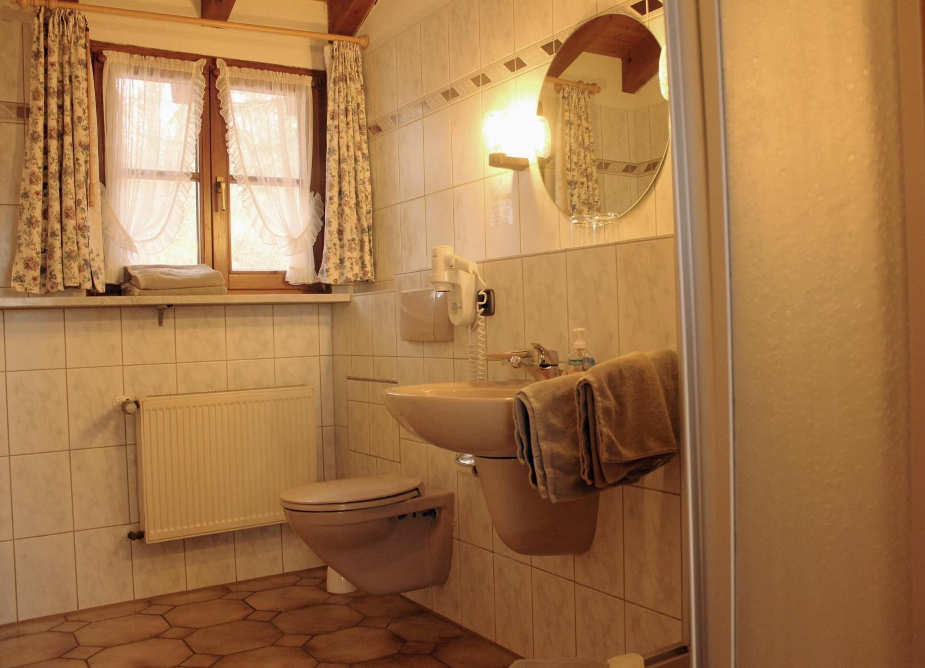 Ein Badezimmer mit Toilette, Waschbecken und einem Fenster mit Vorhängen.