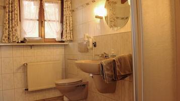 Ein Badezimmer mit Toilette, Waschbecken und einem Fenster mit Vorhängen.