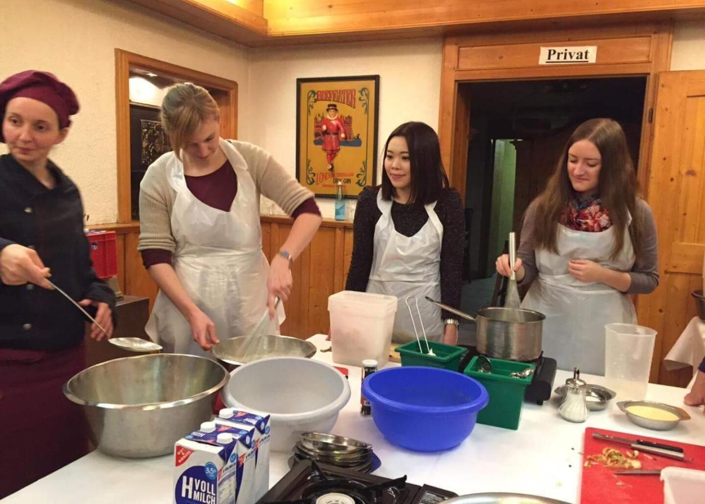 Un grupo de personas en una cocina con utensilios y alimentos sobre la mesa.