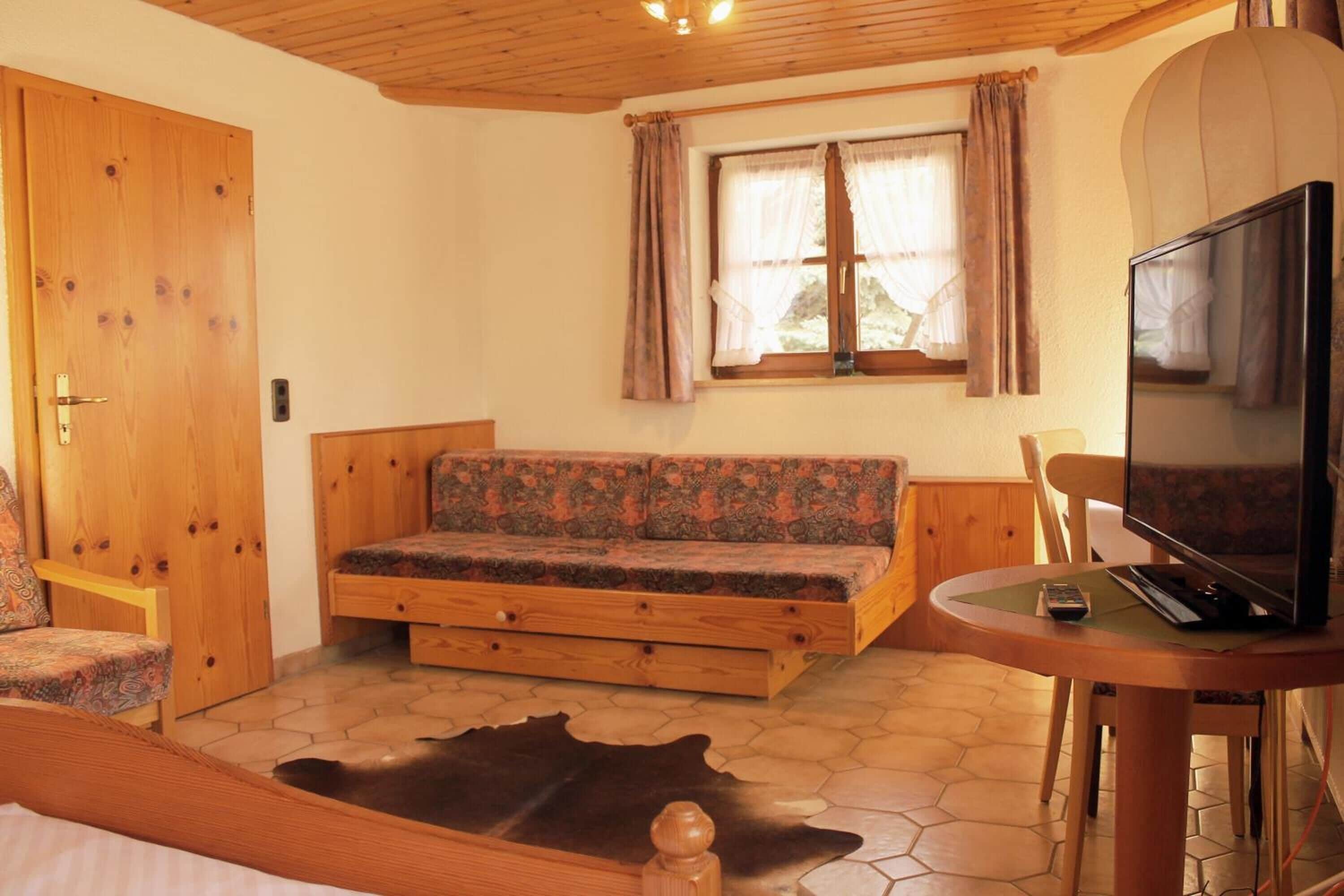 Une pièce confortable avec un canapé, un téléviseur, une porte en bois et une fenêtre avec des rideaux.