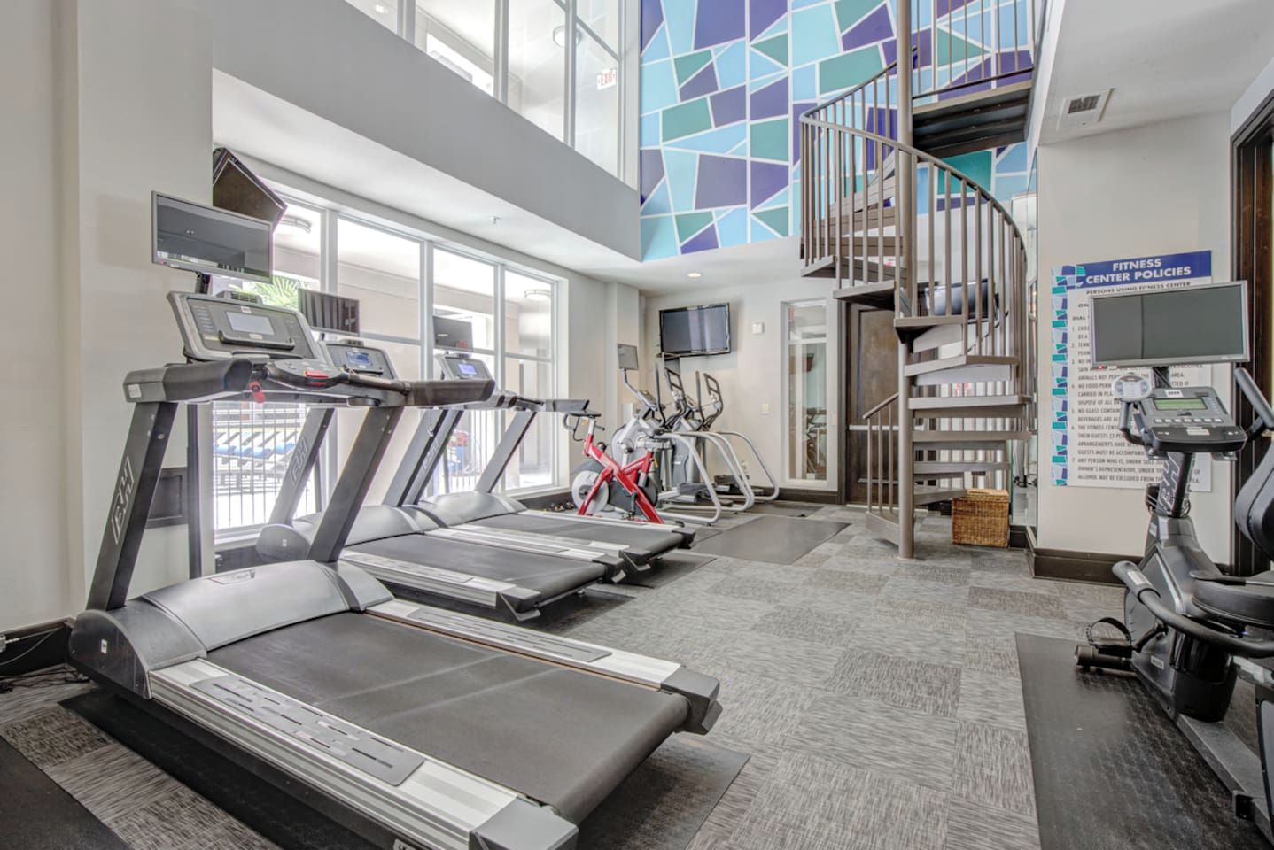 A fitness center with treadmills, stationary bikes, and a staircase.