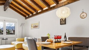 A dining area with a wooden table, grey upholstered chairs, a red decorative pot, and a hanging light fixture.