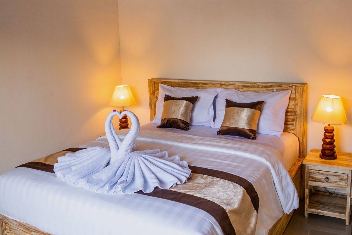 A hotel room with a large bed, two bedside lamps, and a wooden nightstand.