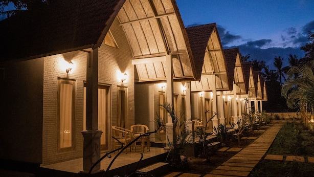 A row of bungalow-style accommodations with individual entryways, each featuring a porch and a single chair. - Kayu Kuning Cottage (Penida Island)