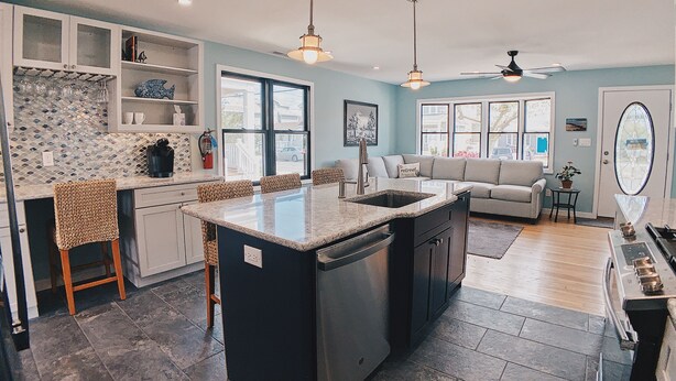 Een moderne keuken met een centraal eiland, inbouwmeubels en een zithoek met een bank en stoelen.