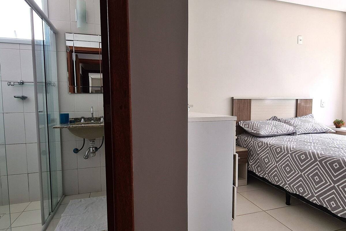 A modern bedroom with a bed, bedside table, and a window.