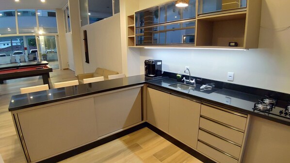 A modern kitchen with a black countertop, beige cabinets, and a coffee maker.