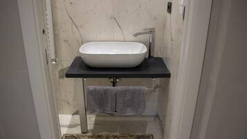 A bathroom with a white sink, black countertop, and a towel rack.