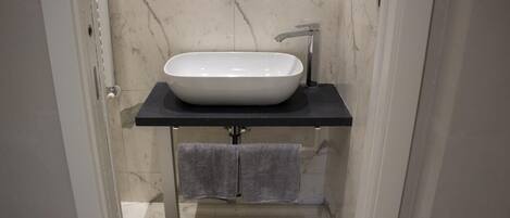 A bathroom with a white sink, black countertop, and a towel rack.