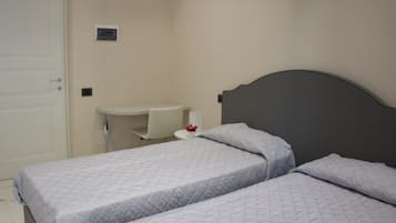 Ein Schlafzimmer mit zwei Betten, einem kleinen Nachttisch, einem Stuhl und einer weißen Tür.