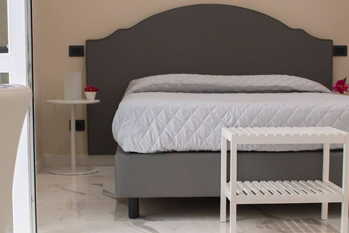 Quarto com uma cama, mesa de cabeceira e uma cadeira.