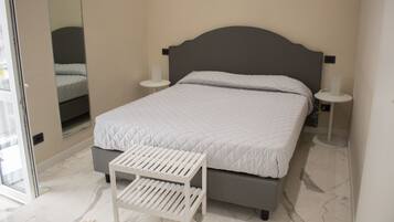Une chambre à coucher avec un lit, des tables de chevet, une commode, un miroir et une fenêtre.