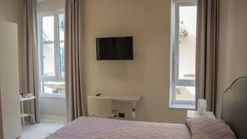 Ein Hotelzimmer mit Bett, Wandfernseher, Schreibtisch und Stuhl.