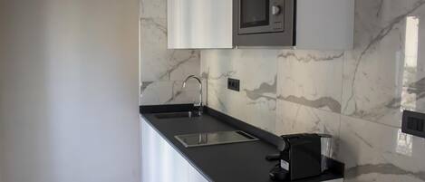 A modern kitchen with a black countertop, white cabinets, and a built-in microwave.