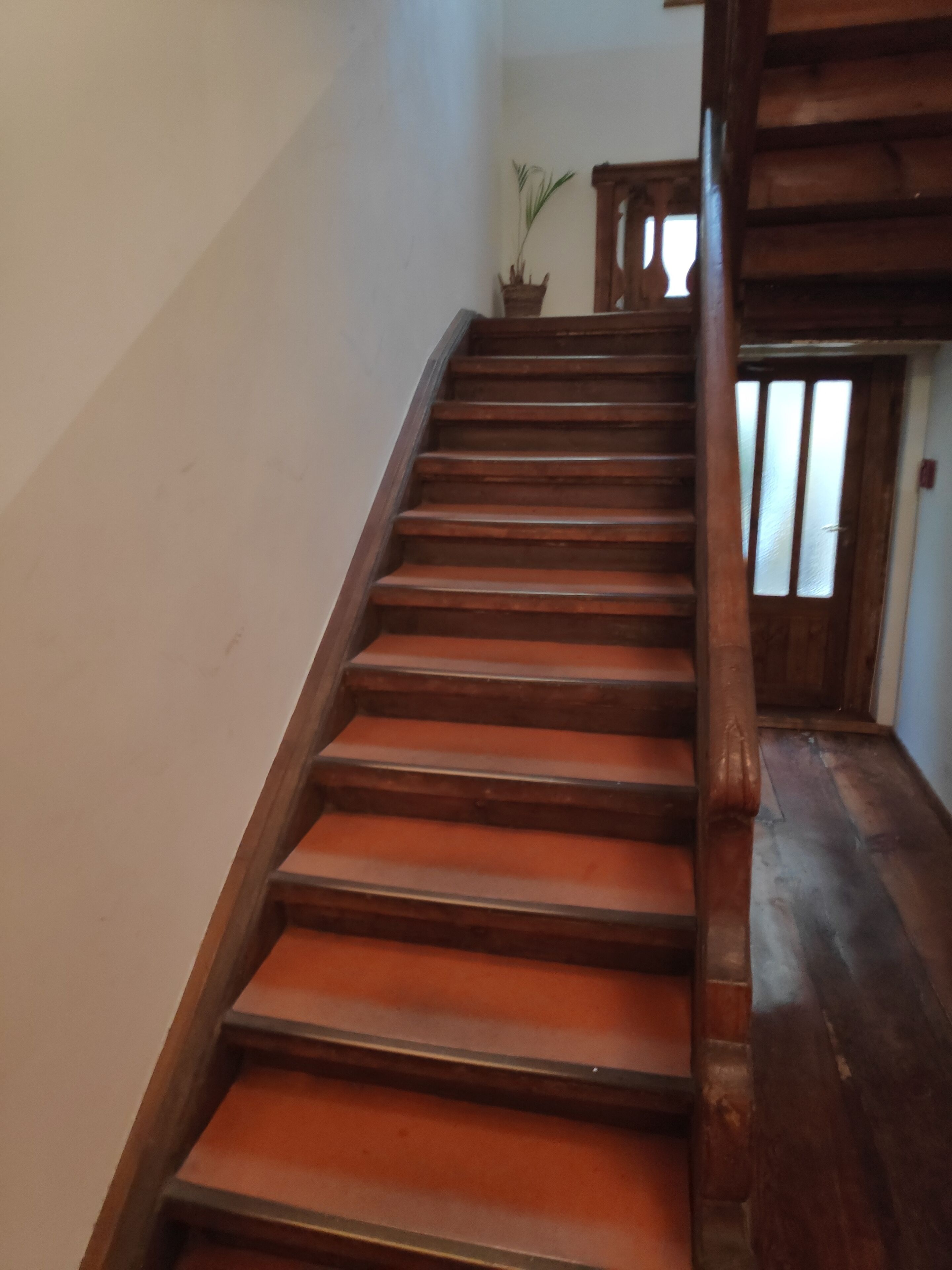 A wooden staircase with a handrail, leading to a door with frosted glass panels.