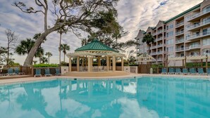 A pool area with a gazebo, lounge chairs, and a multi-story building in the background. - 3209 Windsor Court South - Beautiful Panoramic Oceanfront Views! (Hilton Head Island)