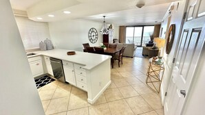 Una cocina moderna con armarios blancos, una isla central y una zona de comedor con candelabro.