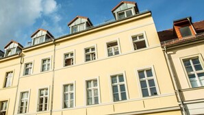 Un edificio de varios pisos con fachada amarilla, múltiples ventanas y ventanas de tejado.