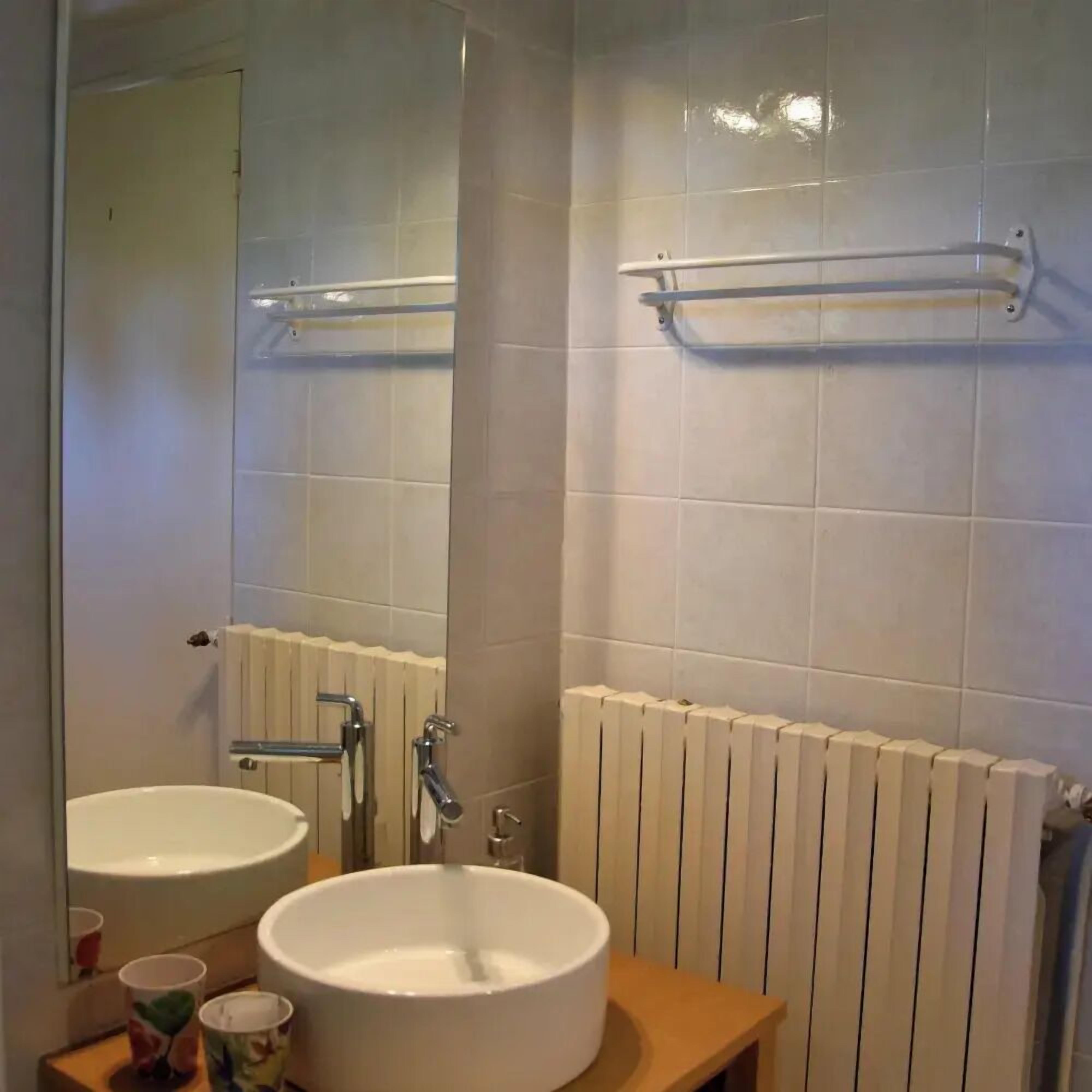 A bathroom with a white sink, a mirror, and a towel rack.
