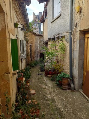 Une ruelle étroite aux murs de pierre, agrémentée de plantes en pot et dotée d’une atmosphère rustique.