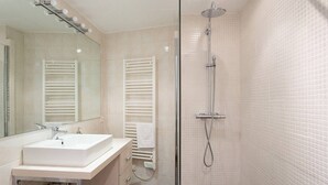 A bathroom with a white sink, mirror, towel rack, and a shower with a handheld showerhead. - Rue d'Antibes: modern apartment ! (Cannes)