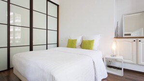 A bedroom with a bed, a nightstand, a mirror, and a large window. - Rue d'Antibes: modern apartment ! (Cannes)