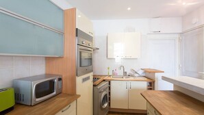 A compact kitchen with a microwave, oven, and washing machine. - Rue d'Antibes: modern apartment ! (Cannes)